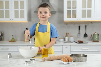 Photo of Little helper. Cute boy making dough for cookies in kitchen at home