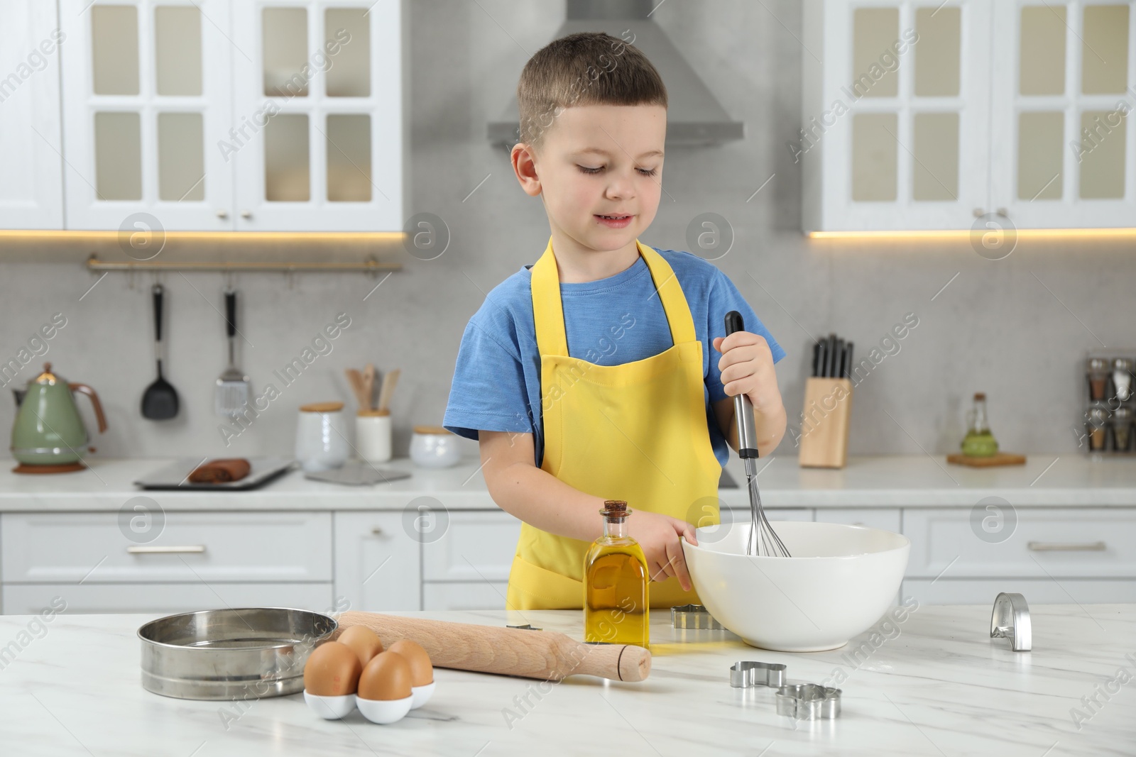 Photo of Little helper. Cute boy making dough for cookies in kitchen at home