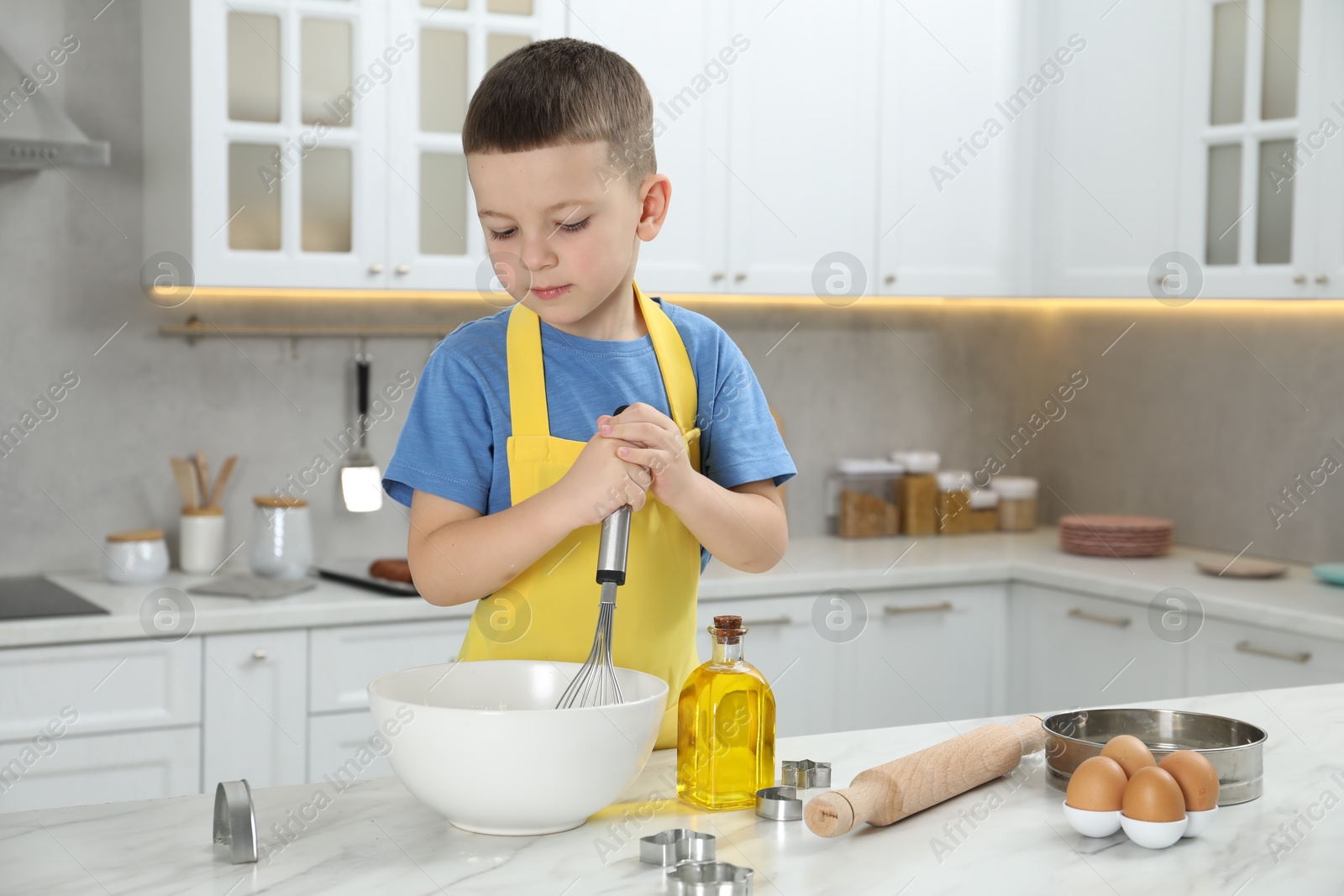 Photo of Little helper. Cute boy making dough for cookies in kitchen at home