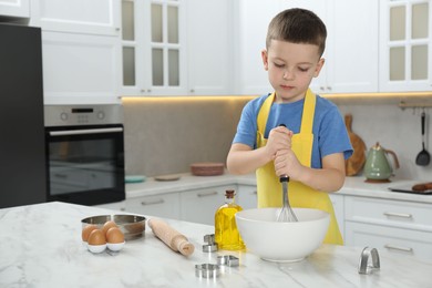 Photo of Little helper. Cute boy making dough for cookies in kitchen at home, space for text