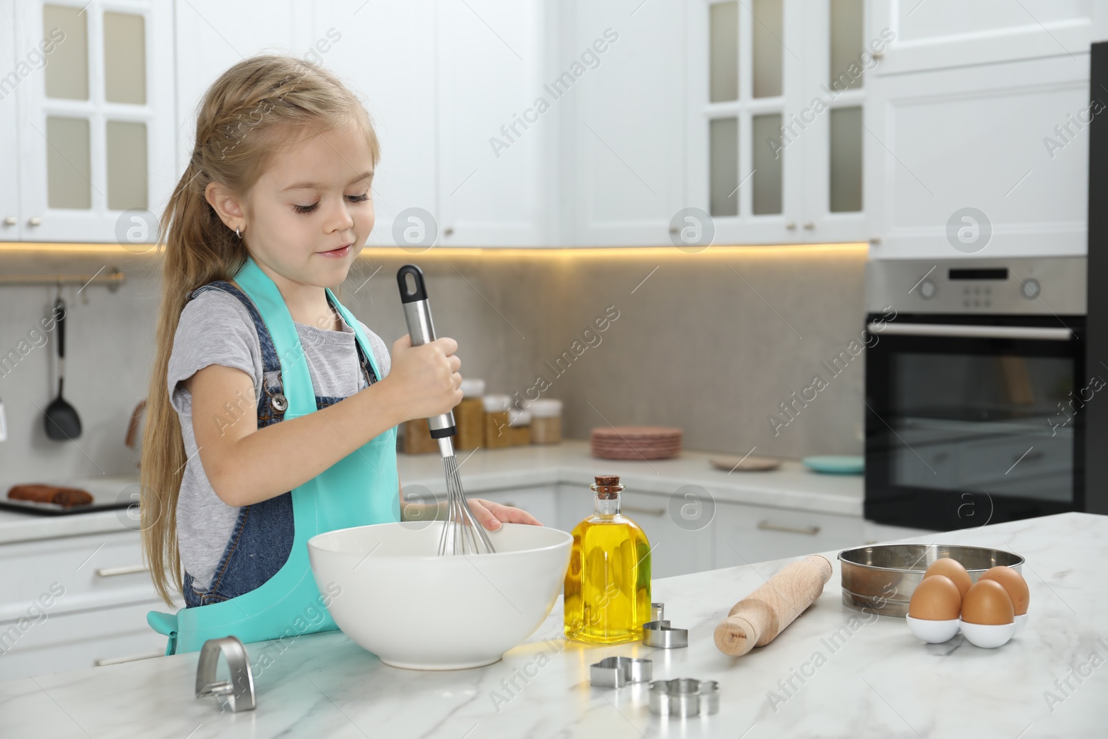 Photo of Little helper. Cute girl making dough for cookies in kitchen at home, space for text