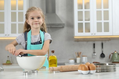 Little helper. Cute girl making dough for cookies in kitchen at home, space for text