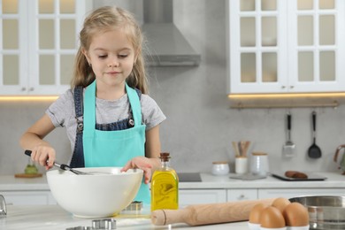 Photo of Little helper. Cute girl making dough for cookies in kitchen at home, space for text