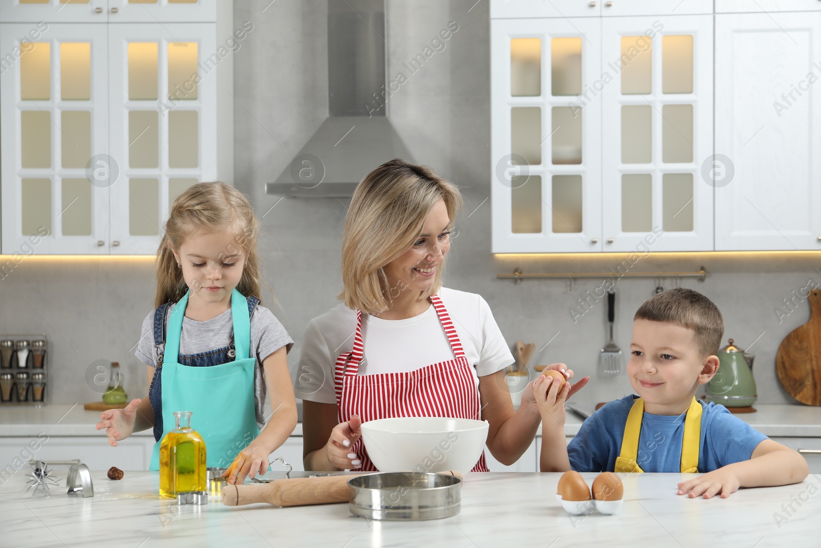 Photo of Children helping their mom making cookies in kitchen at home