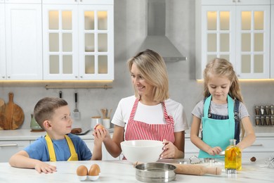 Photo of Children helping their mom making cookies in kitchen at home