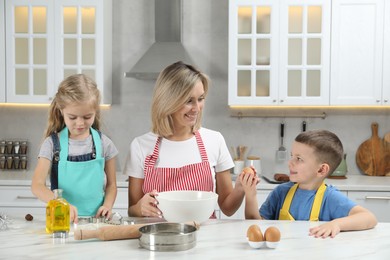 Children helping their mom making cookies in kitchen at home