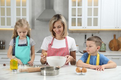 Photo of Children helping their mom making cookies in kitchen at home