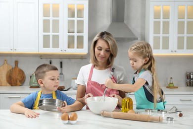 Children helping their mom making cookies in kitchen at home