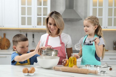 Photo of Children helping their mom making cookies in kitchen at home