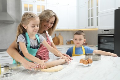 Photo of Children helping their mom making cookies in kitchen at home