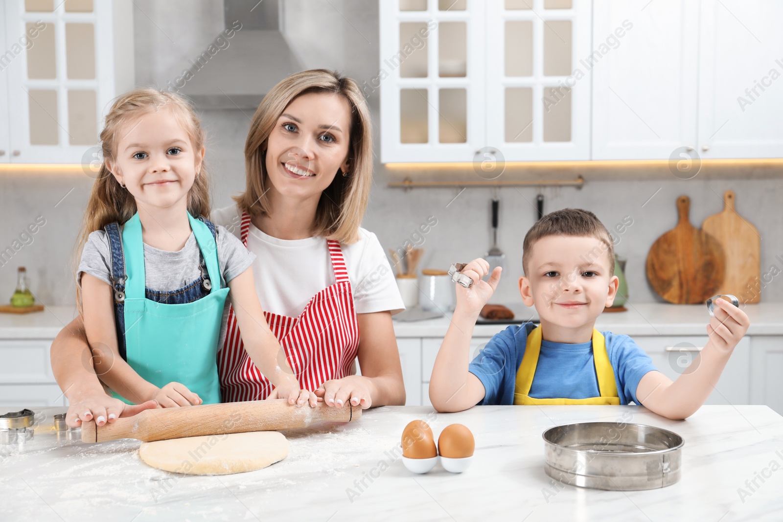 Photo of Children helping their mom making cookies in kitchen at home