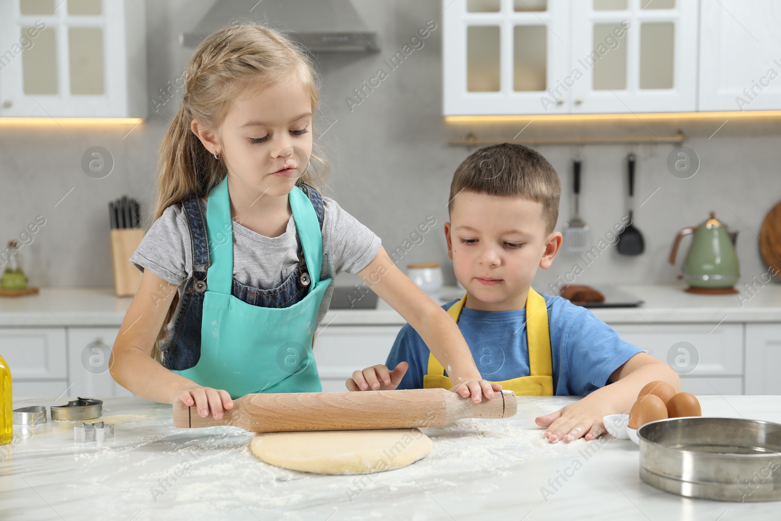 Photo of Little helpers. Children making cookies in kitchen at home