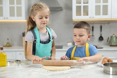 Photo of Little helpers. Children making cookies in kitchen at home