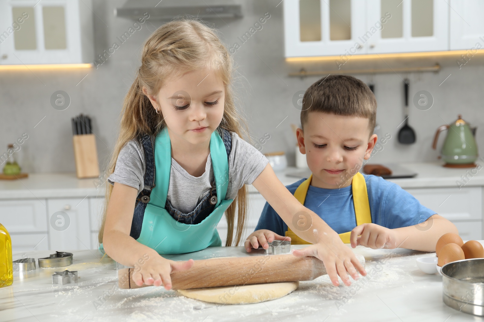 Photo of Little helpers. Children making cookies in kitchen at home