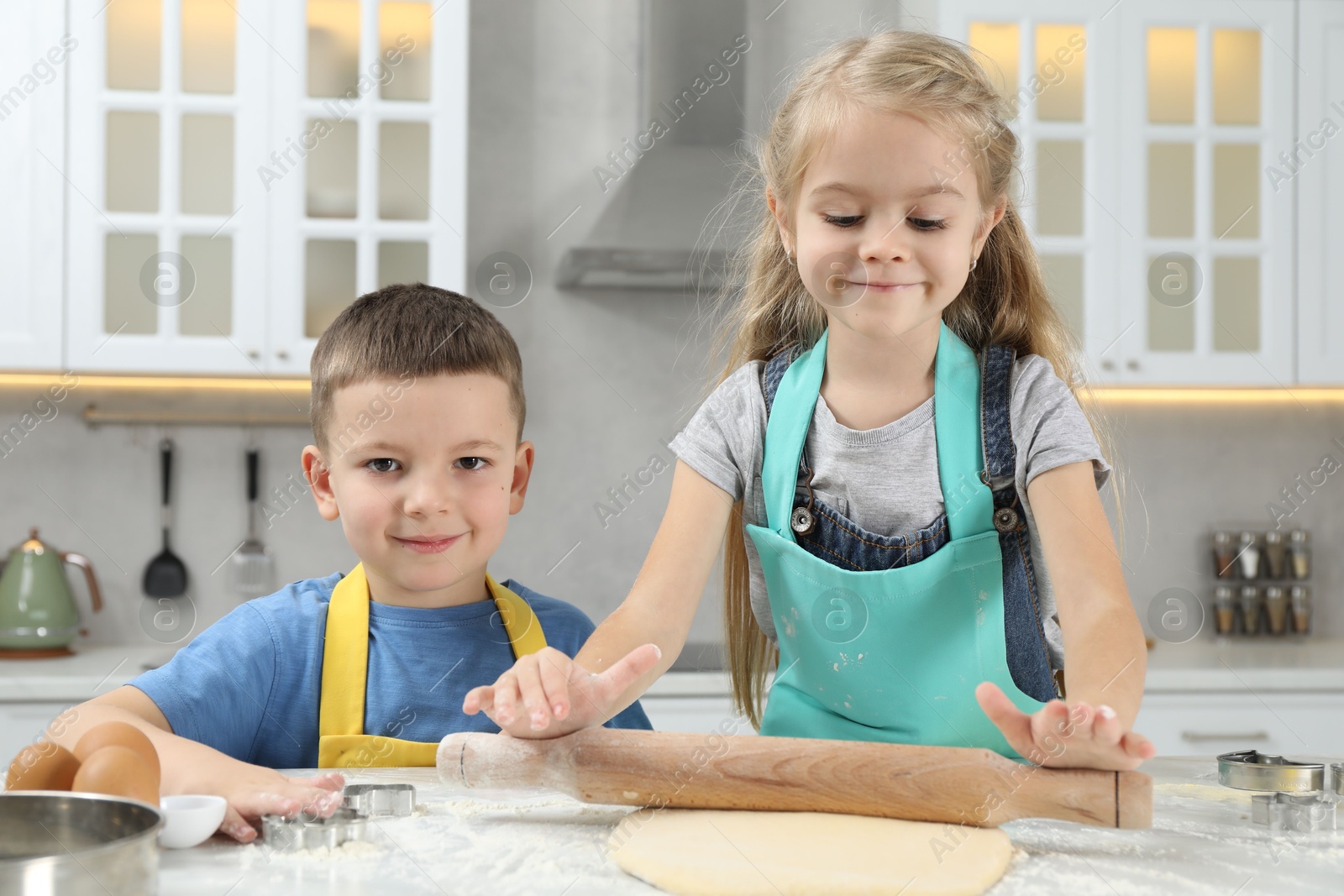 Photo of Little helpers. Children making cookies in kitchen at home