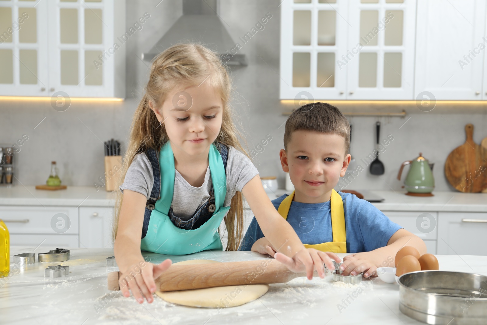 Photo of Little helpers. Children making cookies in kitchen at home