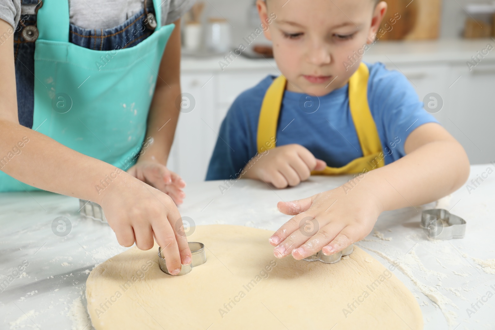 Photo of Little helpers. Children making cookies in kitchen at home, closeup