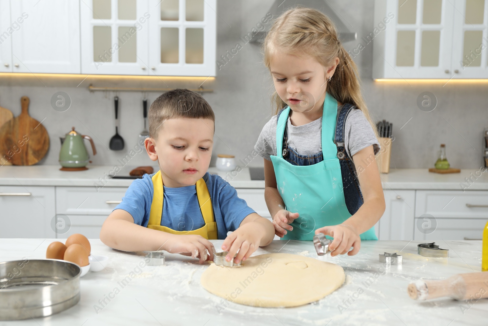 Photo of Little helpers. Children making cookies in kitchen at home