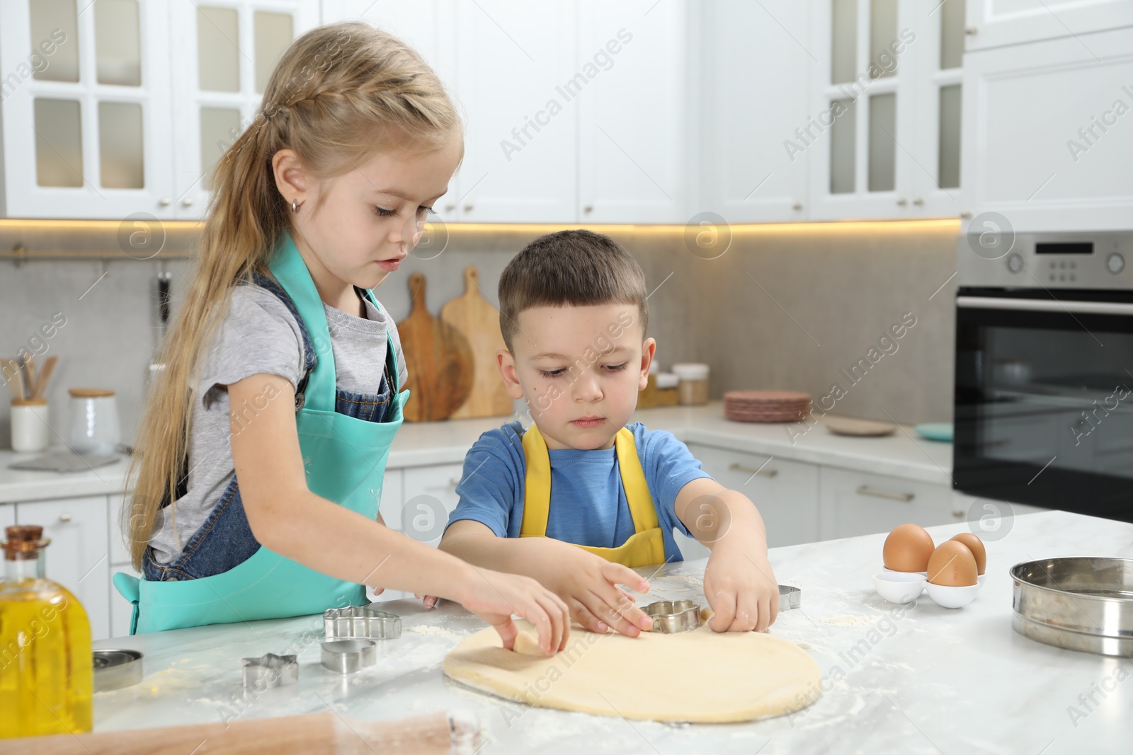 Photo of Little helpers. Children making cookies in kitchen at home