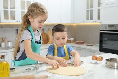 Photo of Little helpers. Children making cookies in kitchen at home