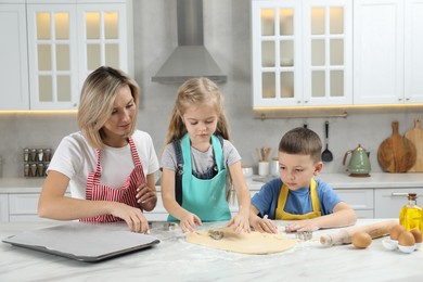 Photo of Children helping their mom making cookies in kitchen at home