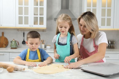 Photo of Children helping their mom making cookies in kitchen at home