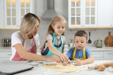 Children helping their mom making cookies in kitchen at home