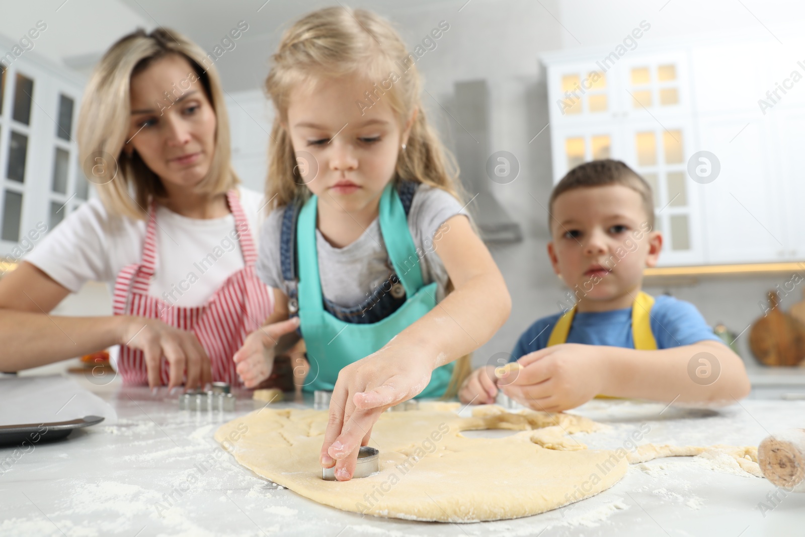 Photo of Children helping their mom making cookies in kitchen at home, low angle view