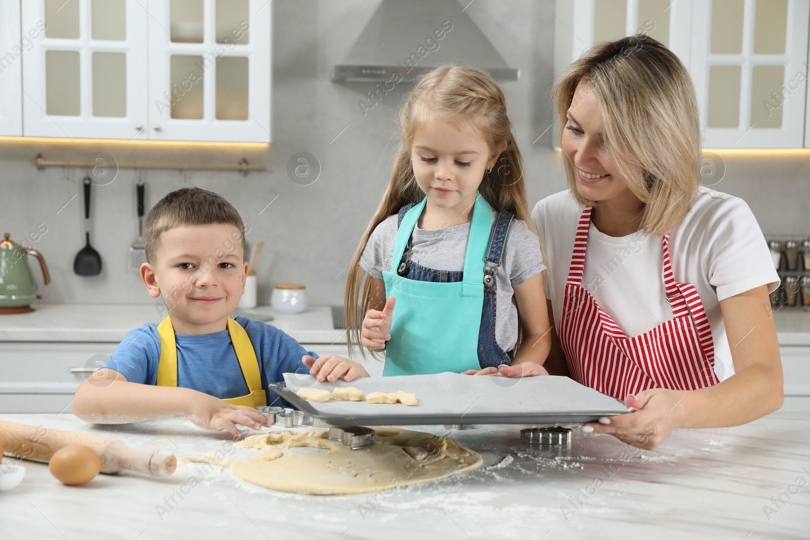 Photo of Children helping their mom making cookies in kitchen at home