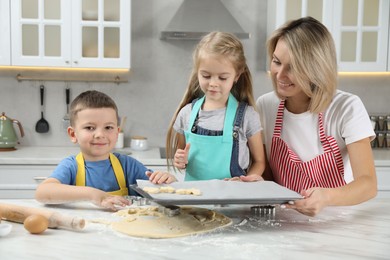 Photo of Children helping their mom making cookies in kitchen at home