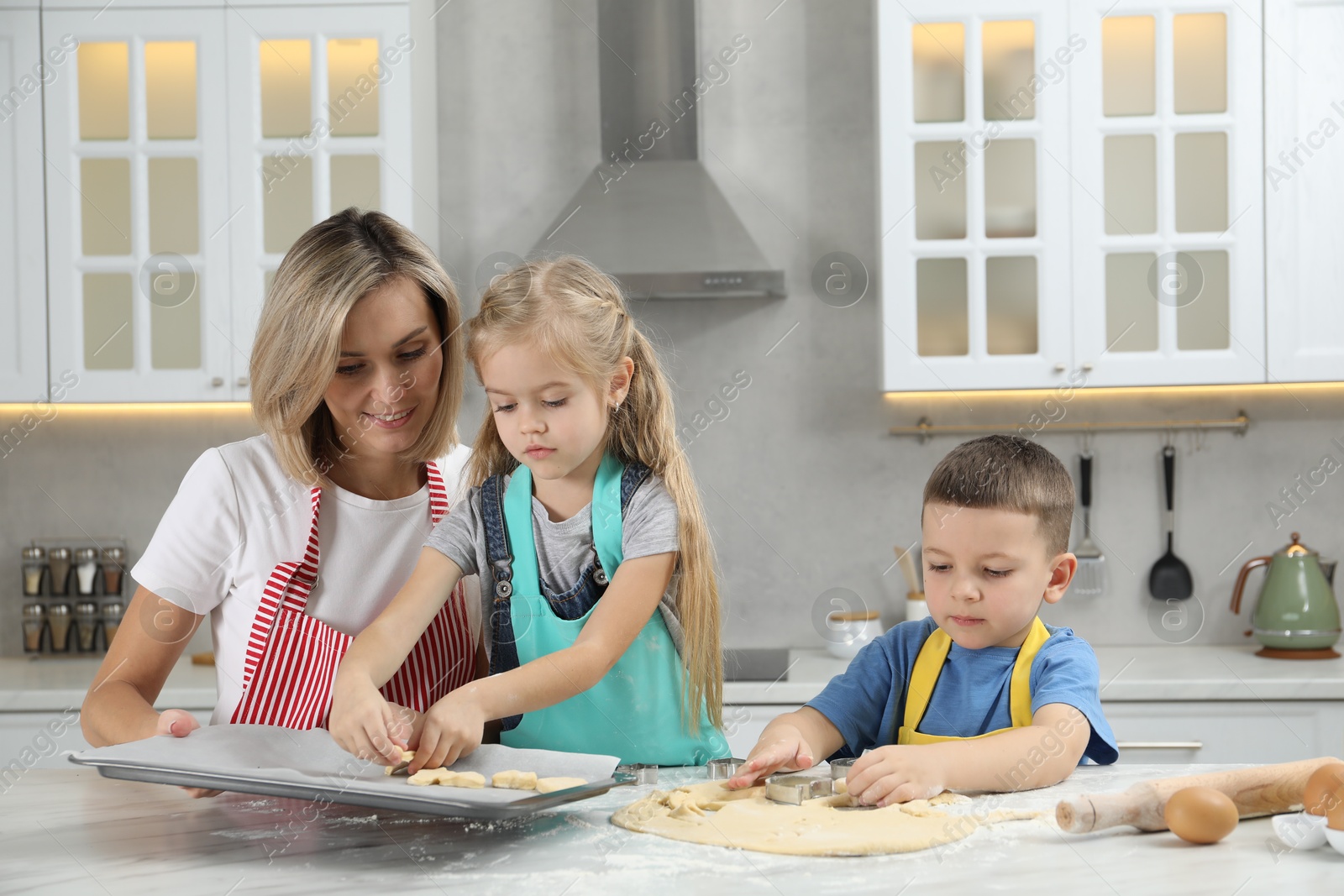 Photo of Children helping their mom making cookies in kitchen at home