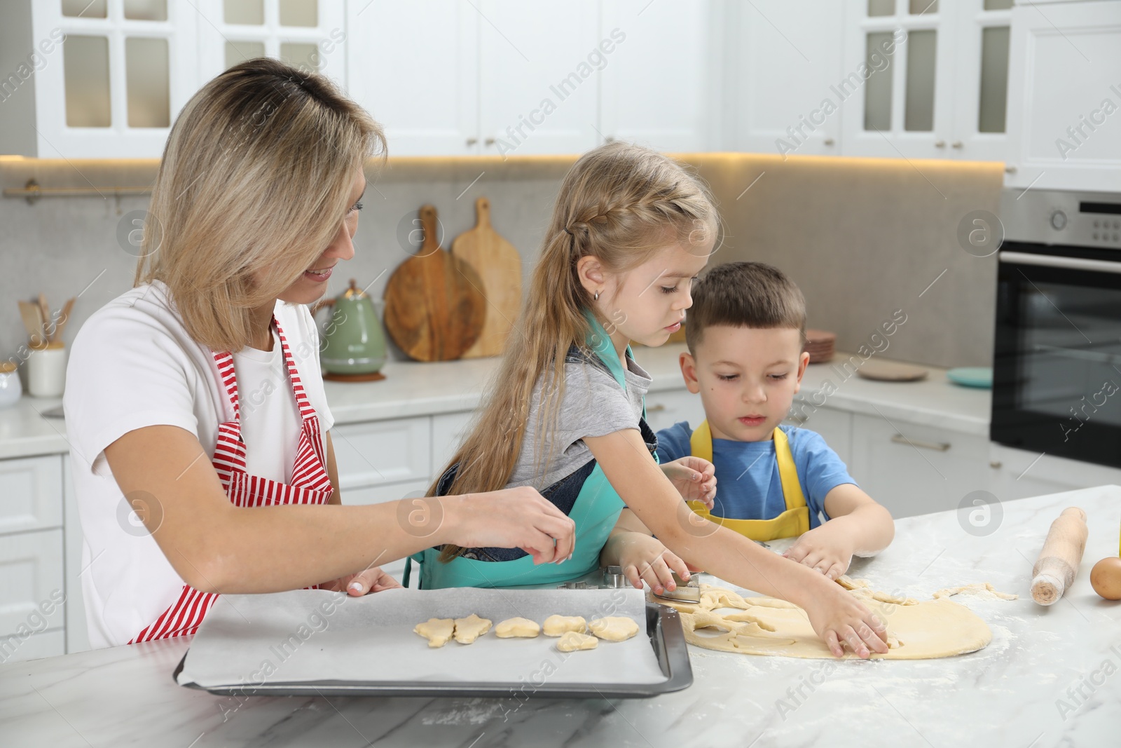 Photo of Children helping their mom making cookies in kitchen at home