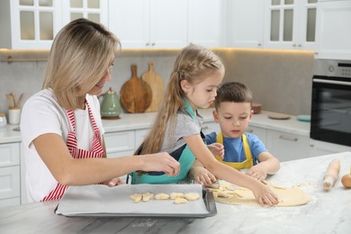 Children helping their mom making cookies in kitchen at home