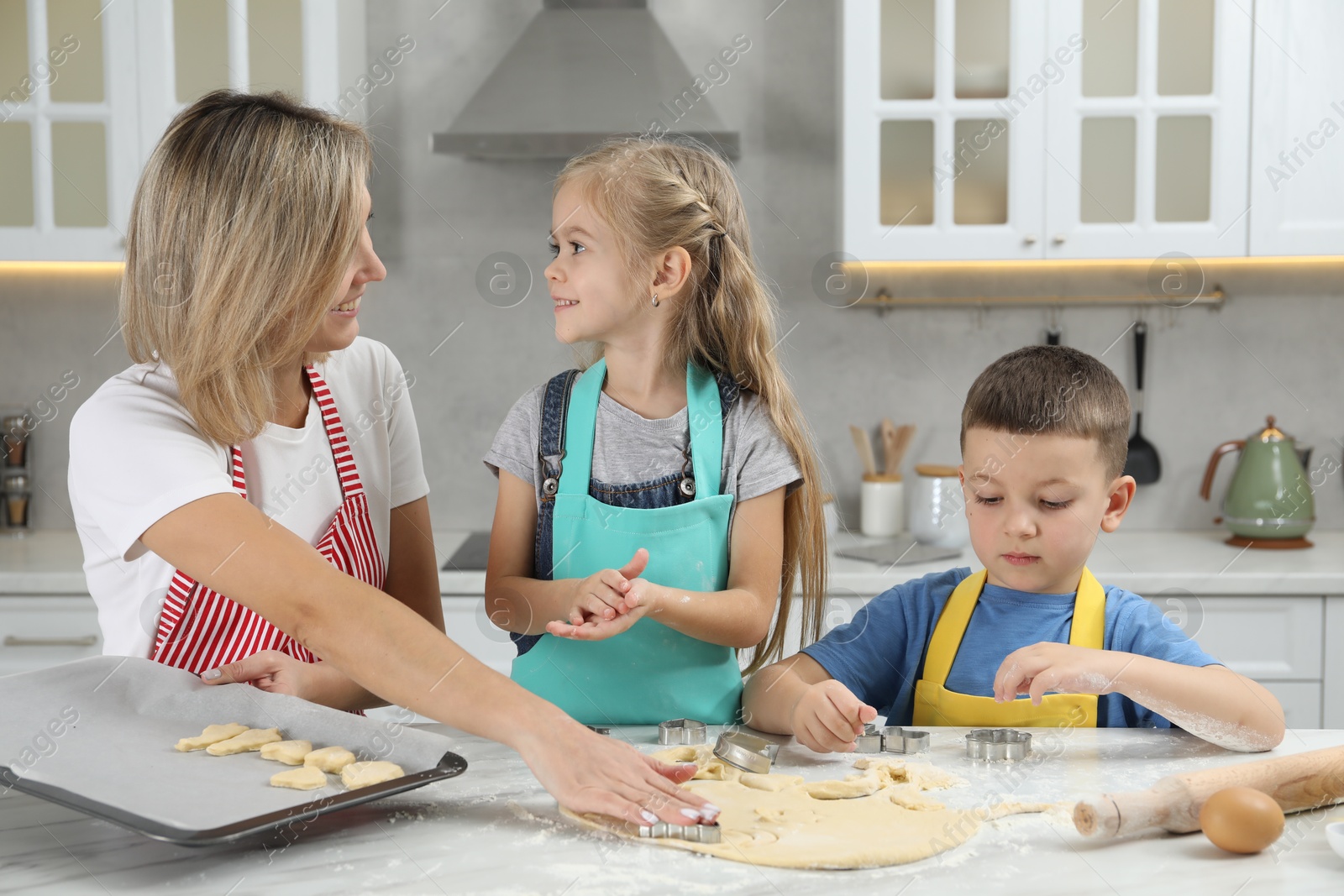 Photo of Children helping their mom making cookies in kitchen at home