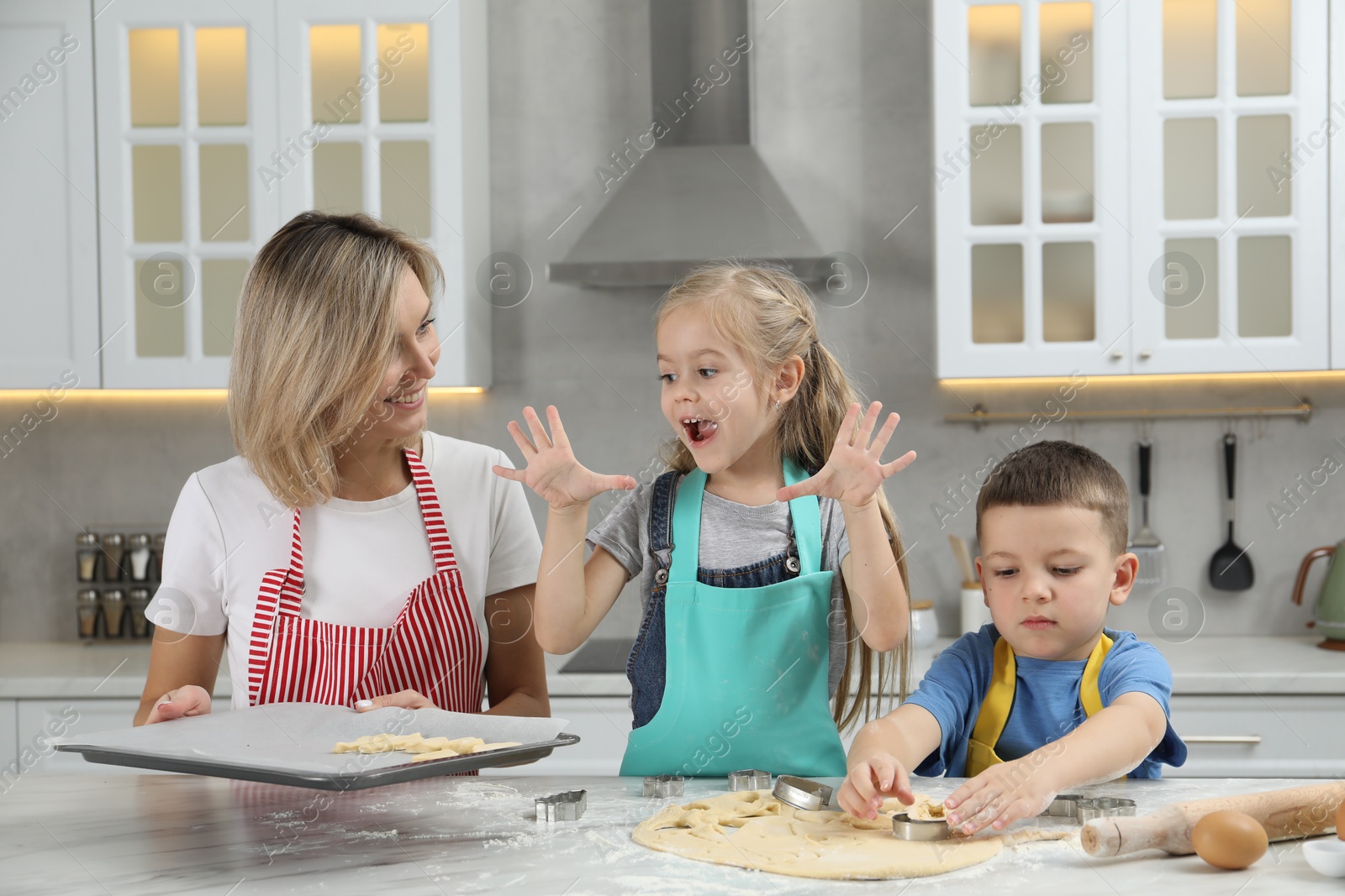 Photo of Children helping their mom making cookies in kitchen at home