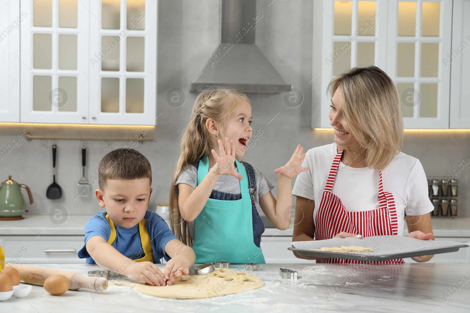 Photo of Children helping their mom making cookies in kitchen at home