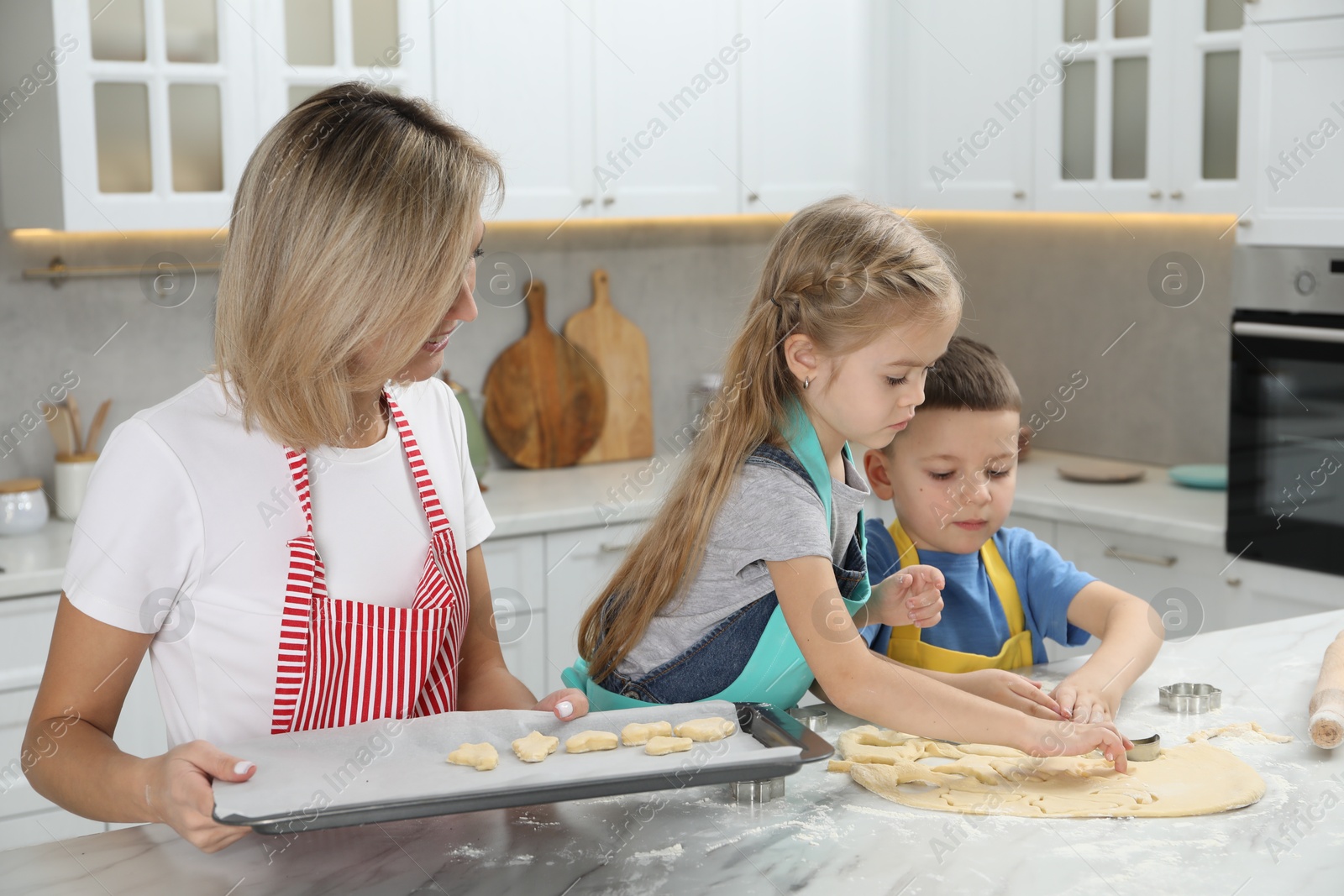 Photo of Children helping their mom making cookies in kitchen at home