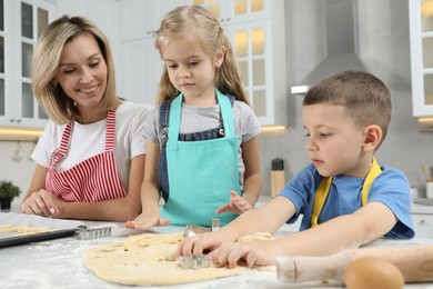 Photo of Children helping their mom making cookies in kitchen at home