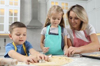 Photo of Children helping their mom making cookies in kitchen at home