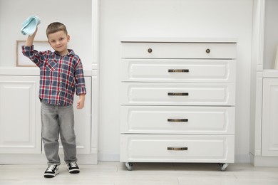 Photo of Little helper. Cute boy wiping dust at home