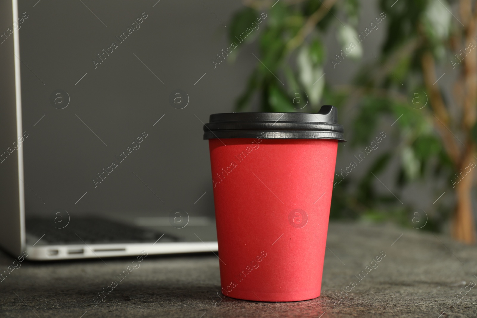 Photo of Paper cup on grey textured table indoors, closeup. Mockup for design