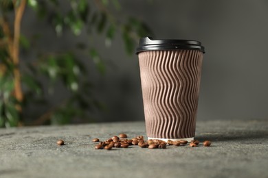 Photo of Paper cup and coffee beans on grey textured table indoors, closeup. Mockup for design