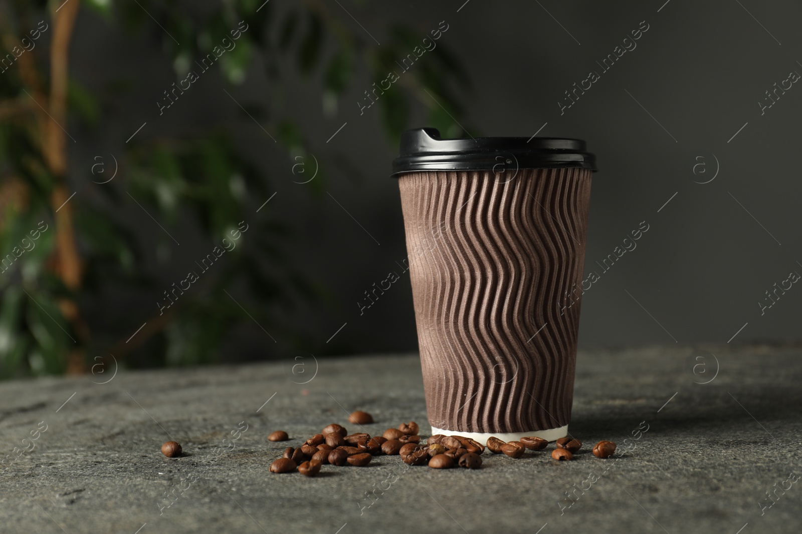 Photo of Paper cup and coffee beans on grey textured table indoors, closeup. Mockup for design