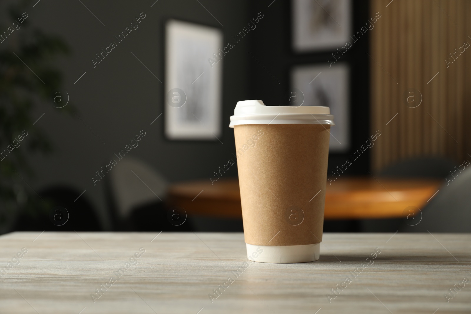 Photo of Paper cup on light wooden table in cafe. Mockup for design