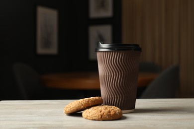 Photo of Paper cup and cookies on light wooden table indoors, closeup. Mockup for design