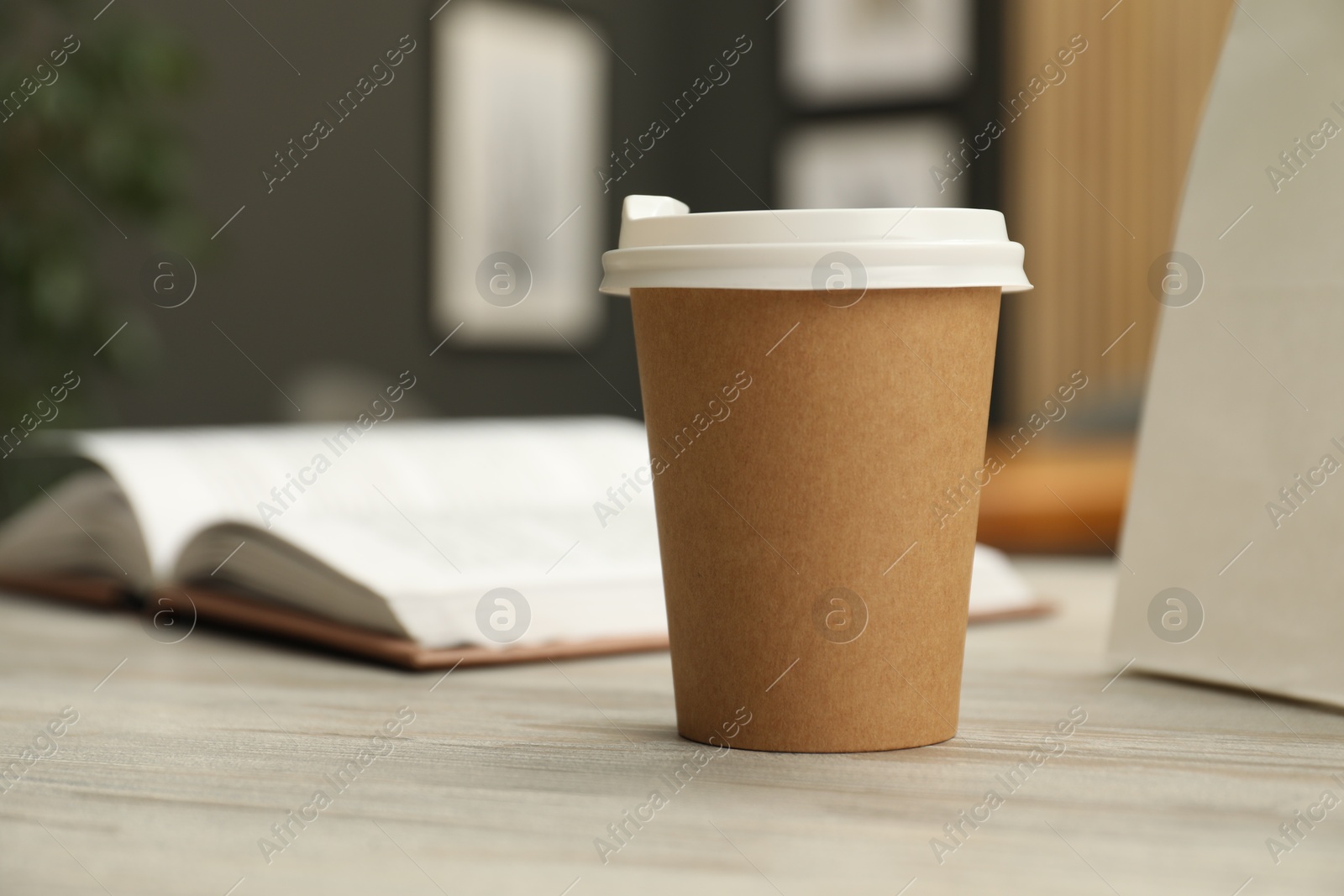 Photo of Paper cup on light wooden table in cafe, closeup. Mockup for design