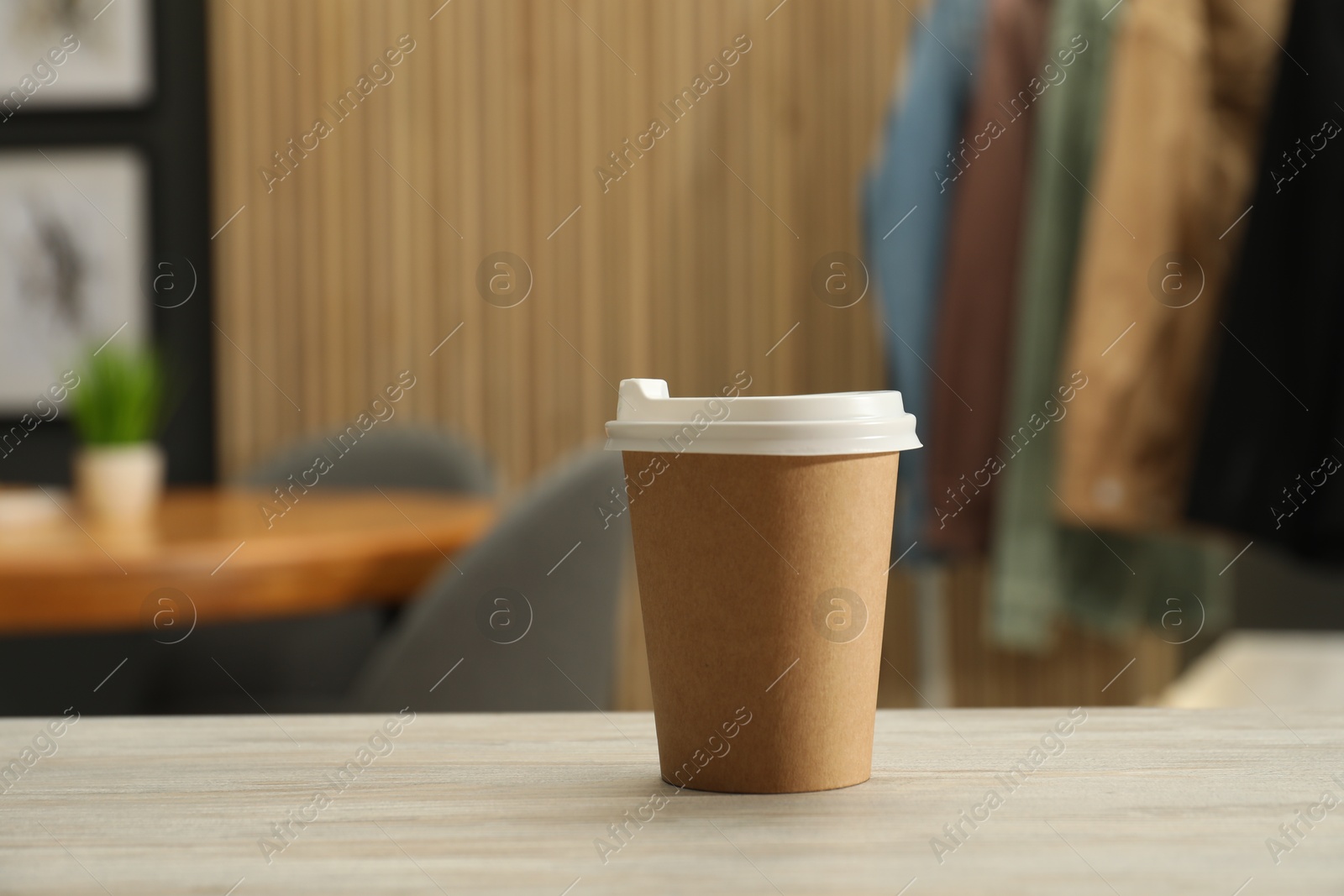 Photo of Paper cup on light wooden table indoors. Mockup for design