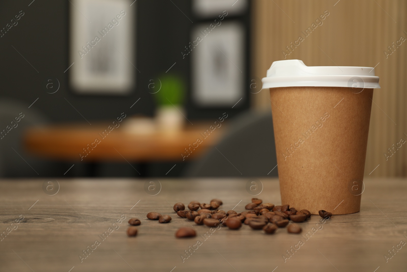 Photo of Paper cup and coffee beans on wooden table indoors. Mockup for design