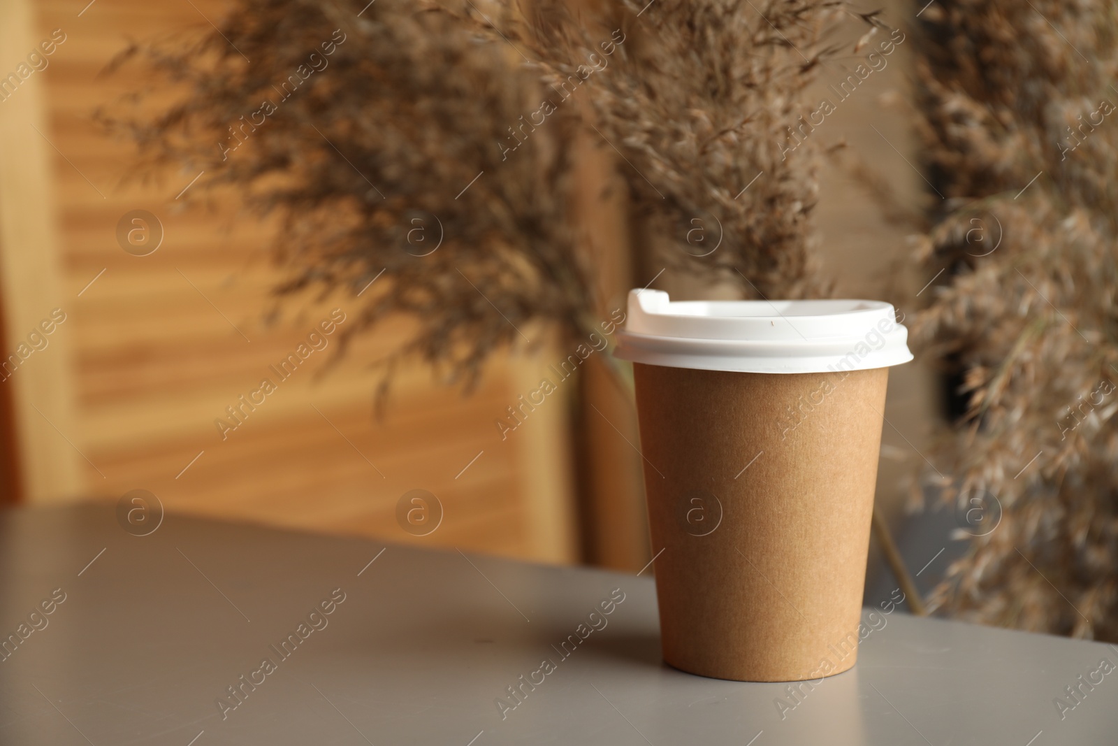 Photo of Paper cup on grey table indoors, closeup. Mockup for design