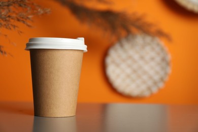 Photo of Paper cup on grey table indoors, closeup. Mockup for design